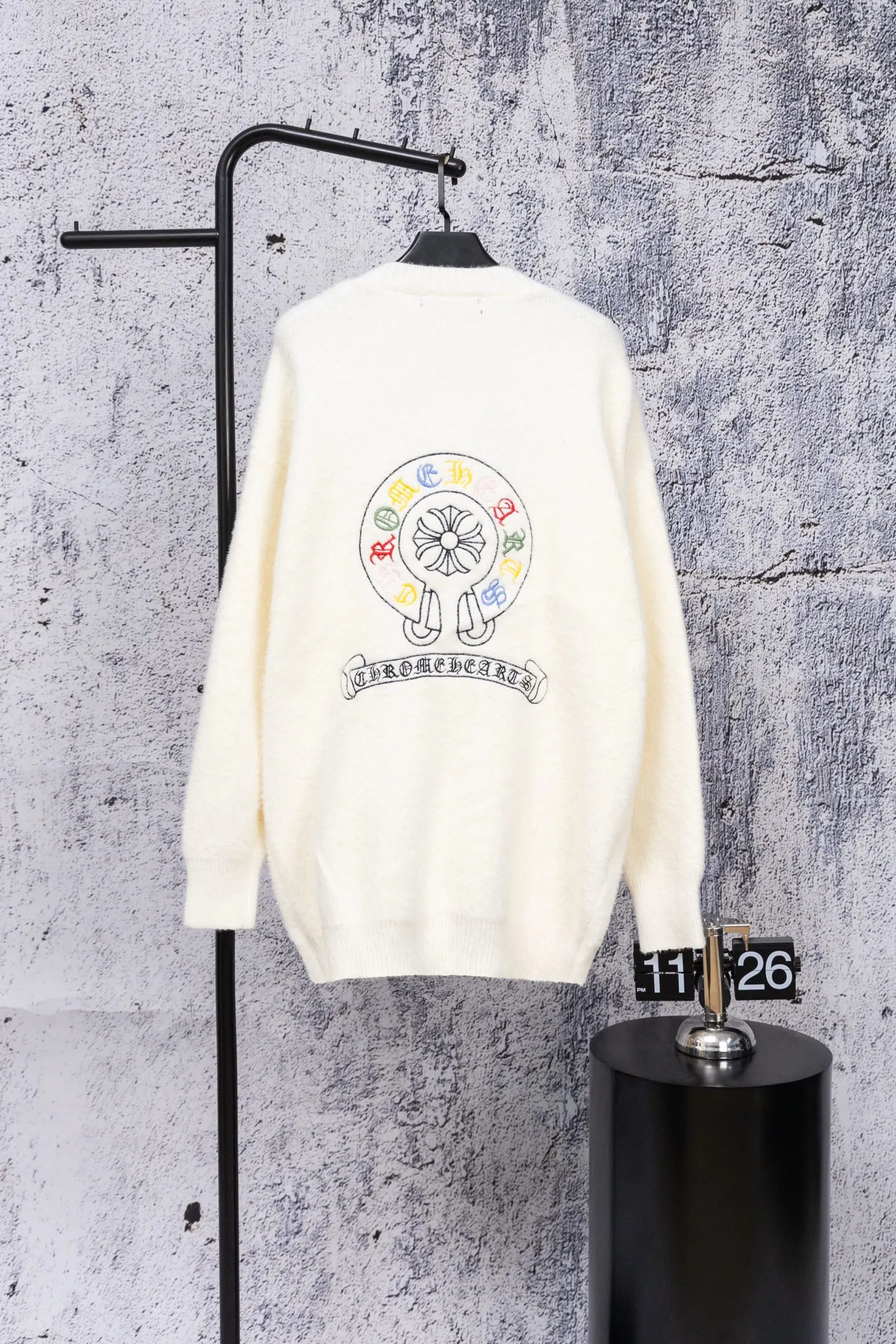 P300 Chrome Hearts CH Chrome Hearts 2026 new cross loose knitted V-neck cardigan Fabric: Made of plush textured knitted material, soft to the touch and with a lazy atmosphere; Decoration: Red, yellow, and black cross ornaments on the chest, paired with brand logo patches, which are iconic elements of street fashion brands (such as Chrome Hearts style), enhancing visual recognition; Version: Loose version + single-row metal button design, combining casual feeling and practicality. 2. Style and Adaptation Style: It combines dark street style and gentle knitted texture, which belongs to the tone of "sweet and cool mix"; Scenario: Can be worn with a T-shirt/suspender to create a daily street look, or can be layered with a shirt for light casual wear. Color: Black White Size: M L XL